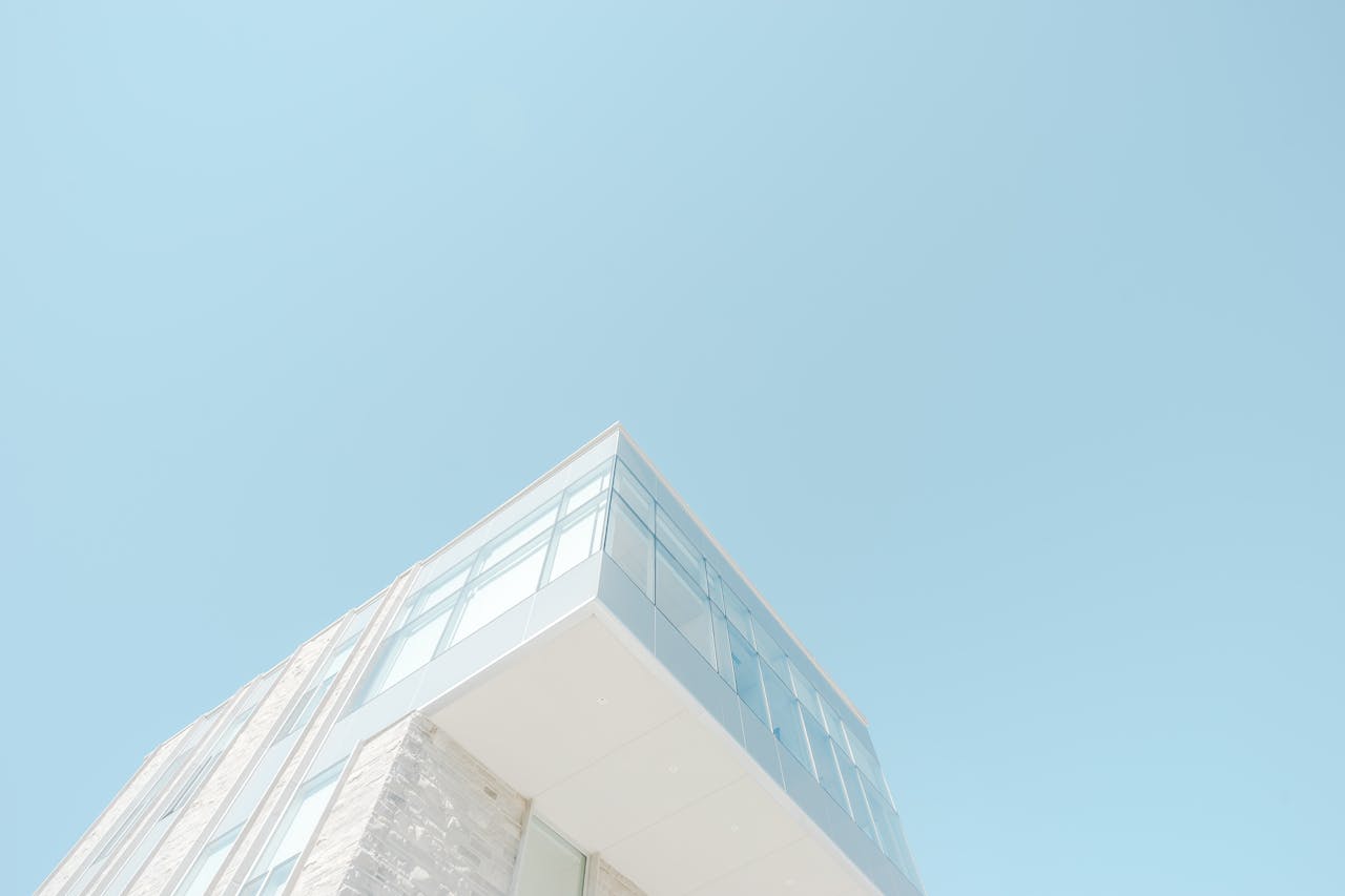 about-02 A low-angle shot of a modern building with a glass facade against a bright blue sky in London, Canada.