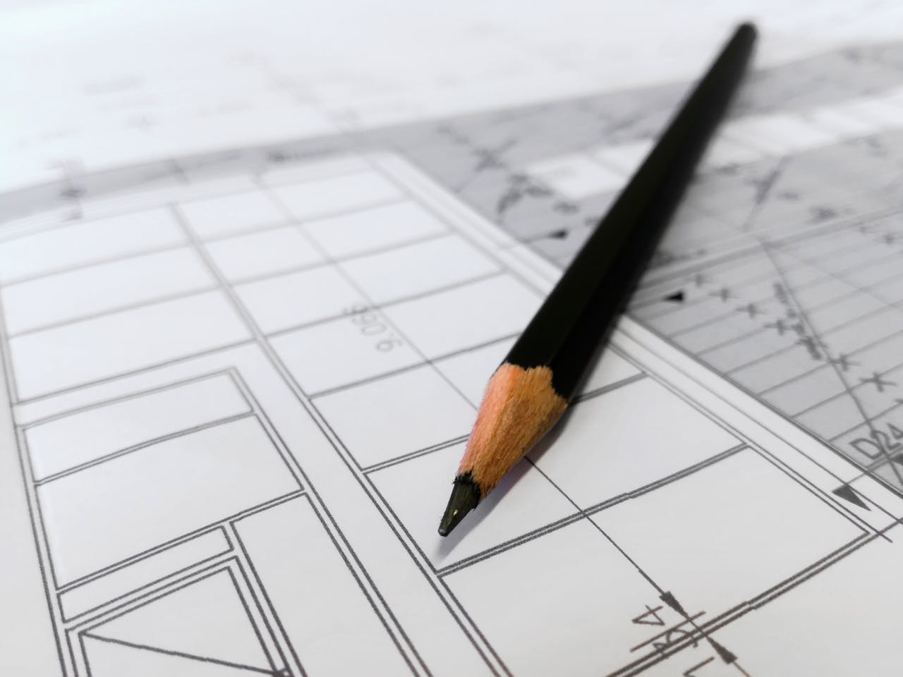 hero-about Detailed image of a black pencil resting on architectural blueprints, ideal for design and planning themes.