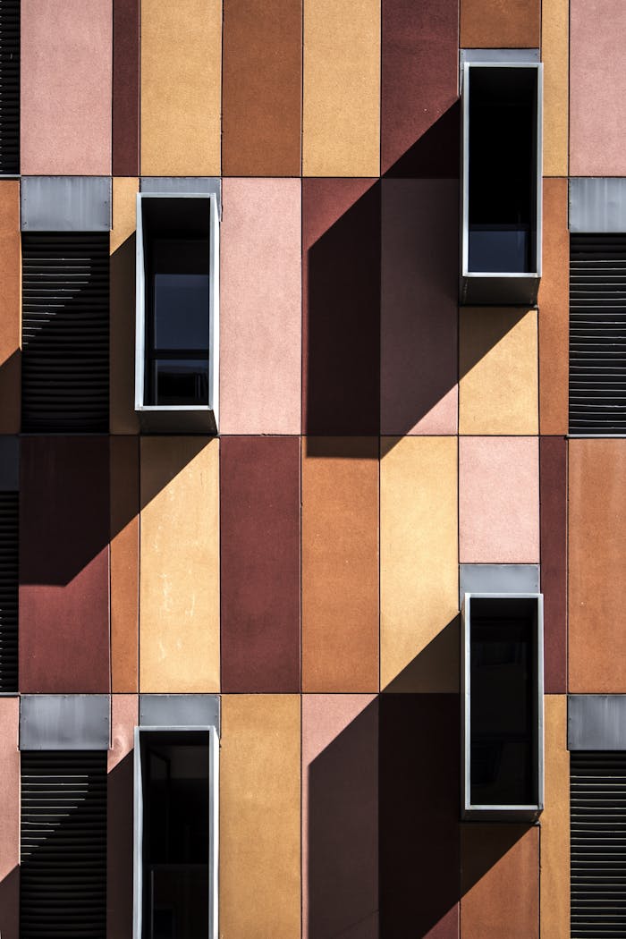 services-02 Colorful modern facade with geometric design and shadows highlighting windows.
